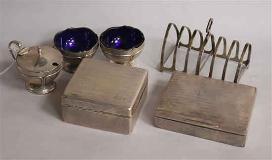 A George V silver three piece condiment set, two silver cigarette boxes and a silver seven bar toastrack.